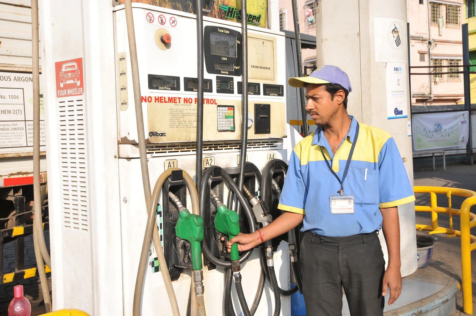 A petrol station attendant standing by the fuel pumps